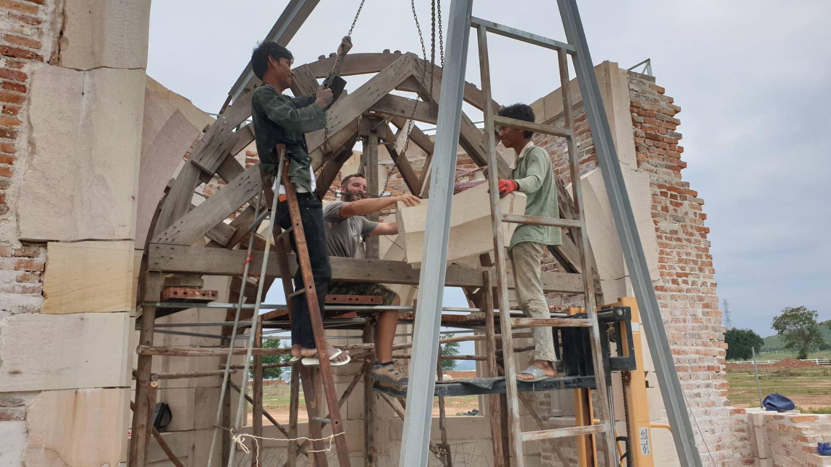 Two Thai stonemasons and the French master raising a rib stone